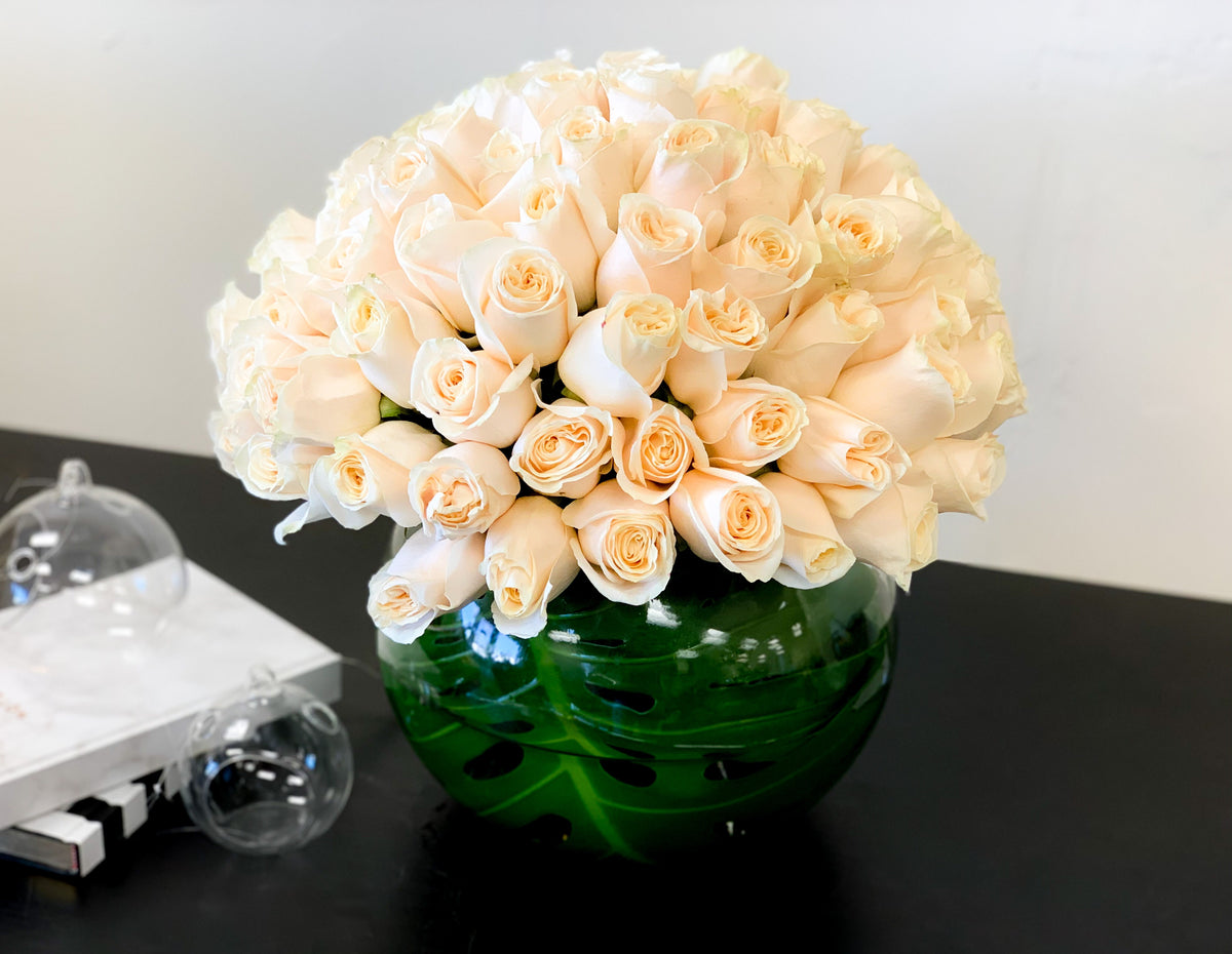 100 White Roses in a clear glass fishbowl vase