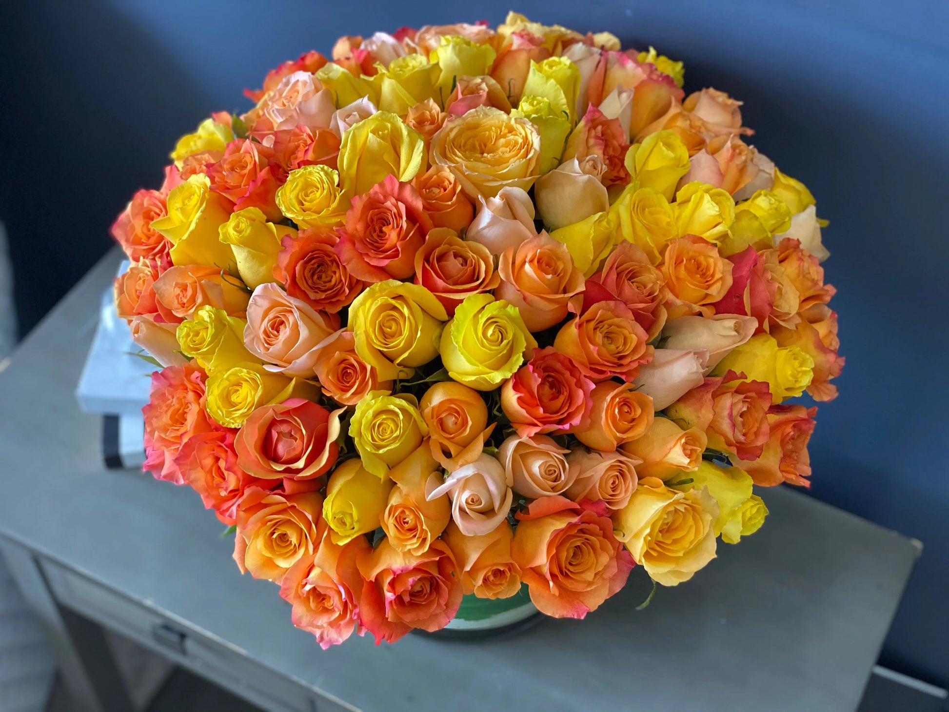 100 colorful roses arranged in a lush rounded floral design
