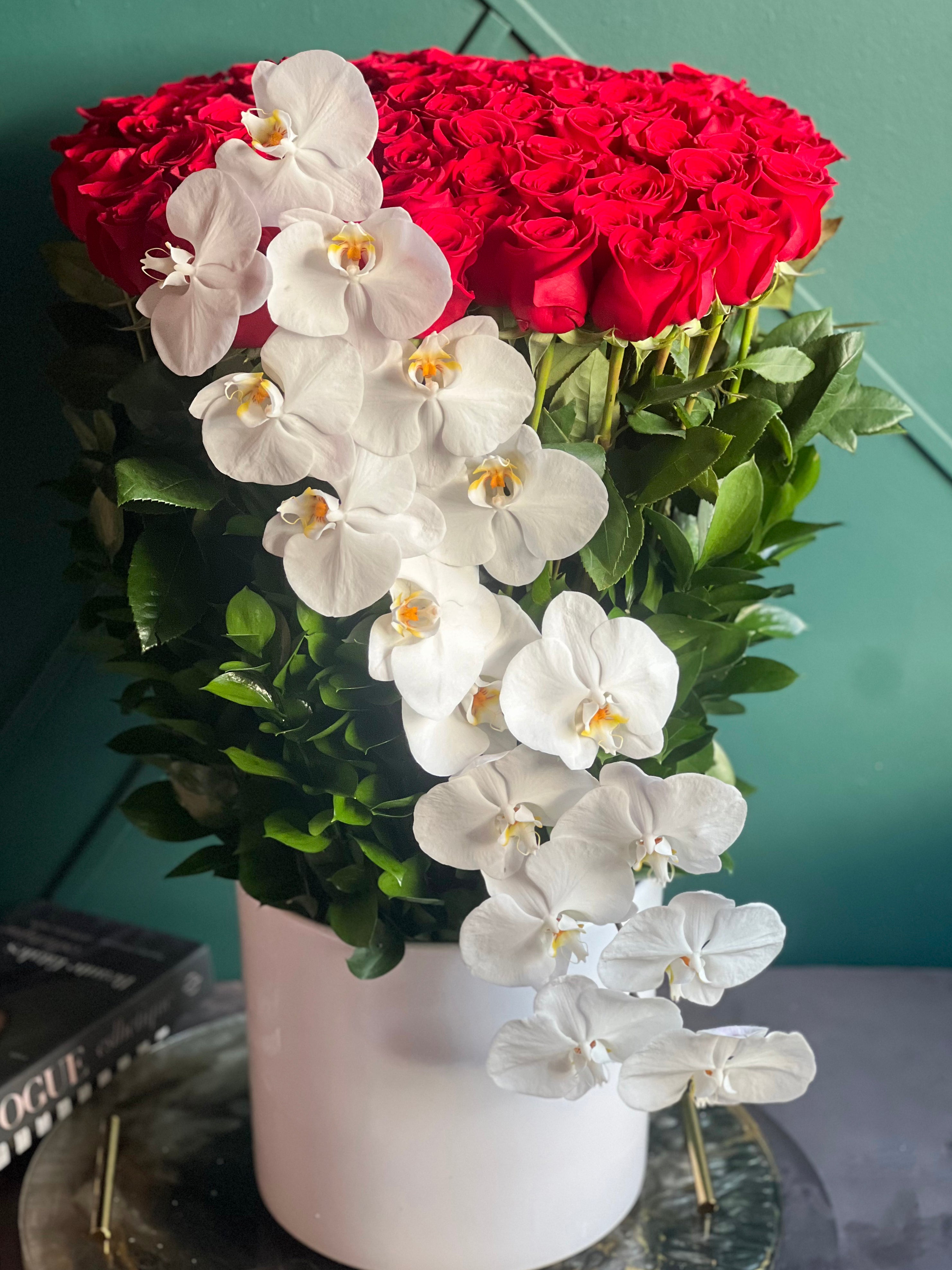 100 red roses with cascading white orchids in a tall vase