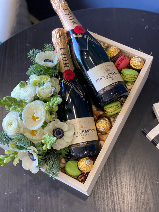 Wooden box with champagne, flowers and sweets