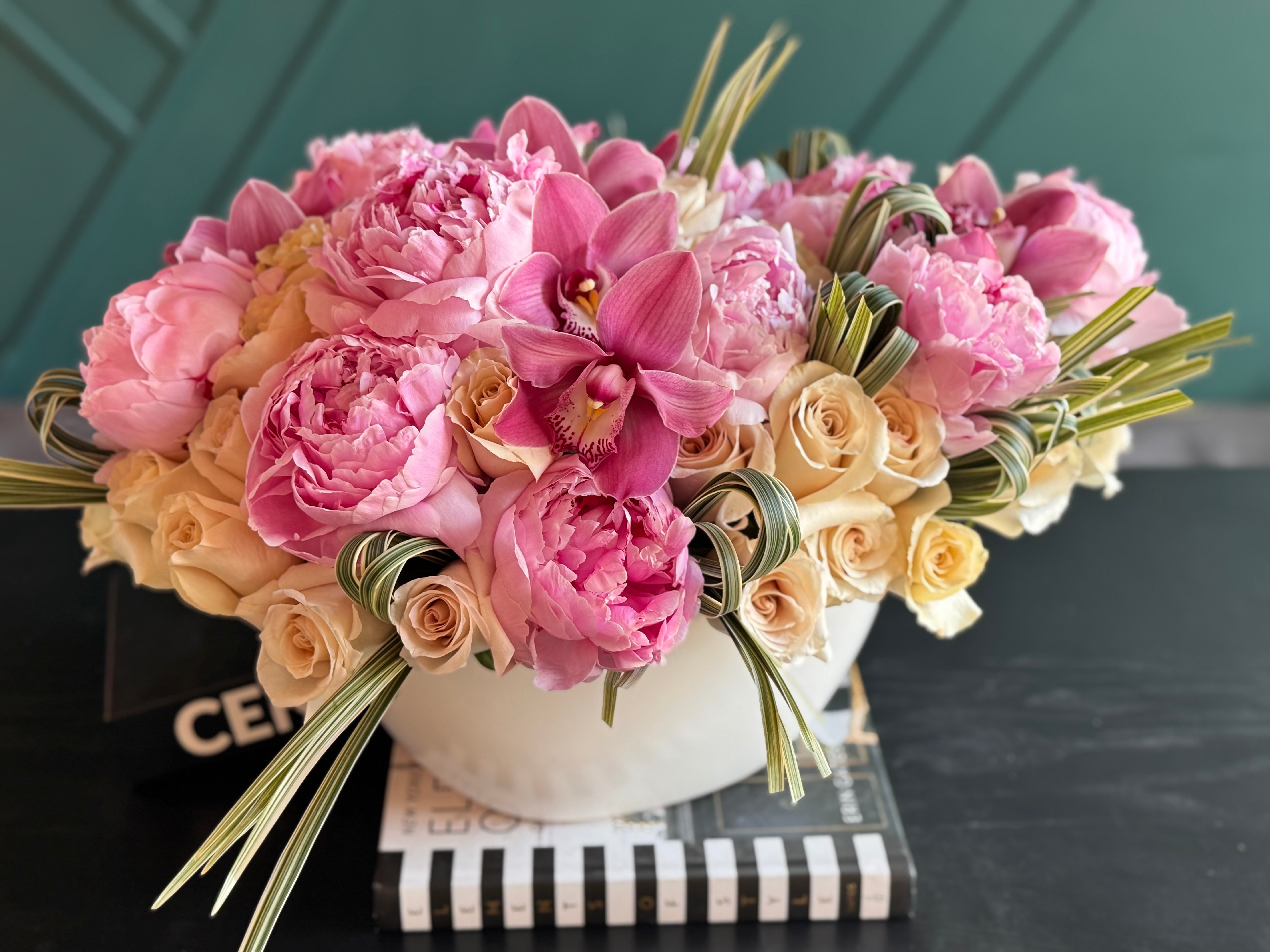 Ceramic vase flower arrangement with orchids peonies and designer greenery