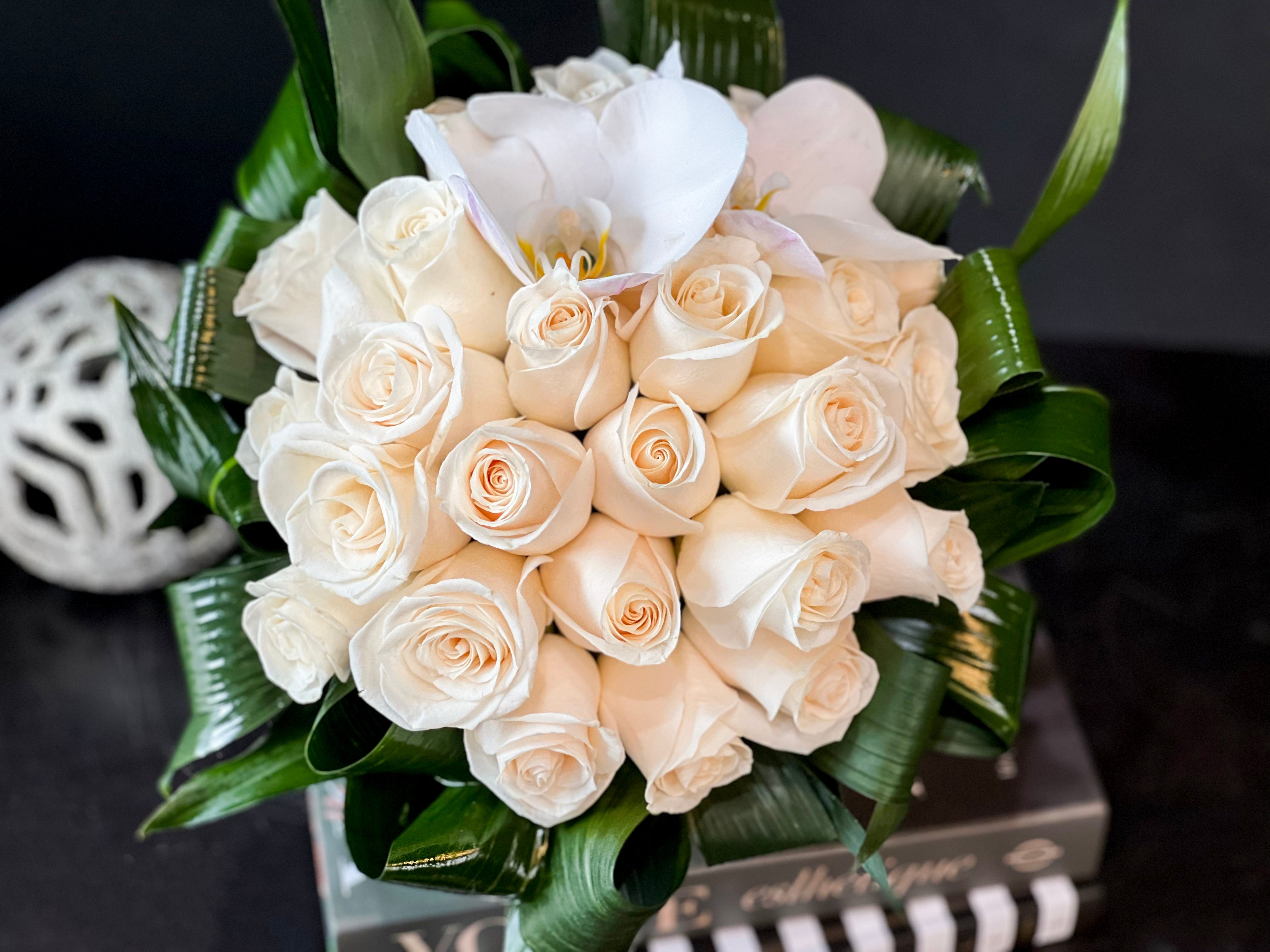 Classic arrangement of white roses in a clear fishbowl vase