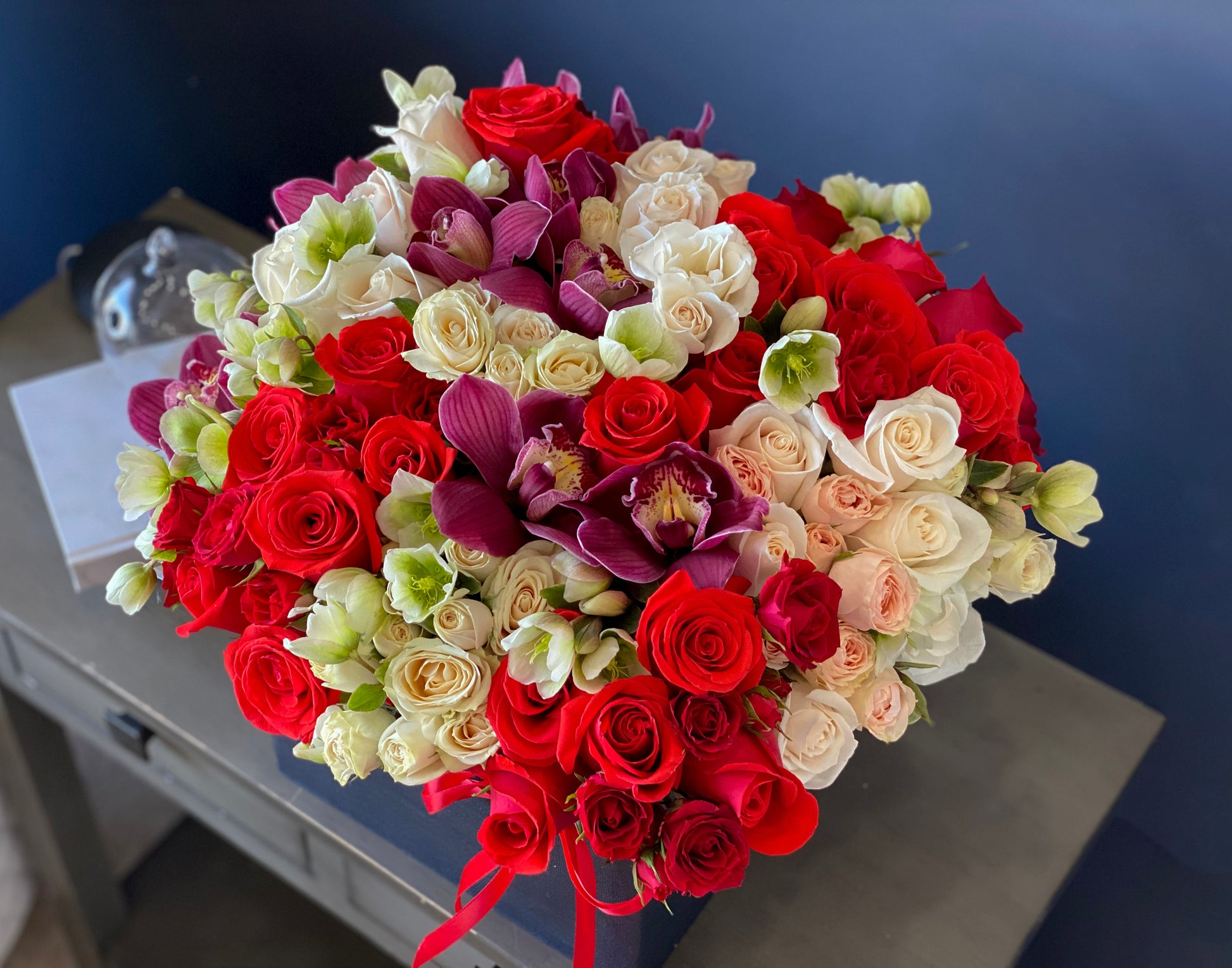 Designer flower box with red roses cymbidium orchids and greenery