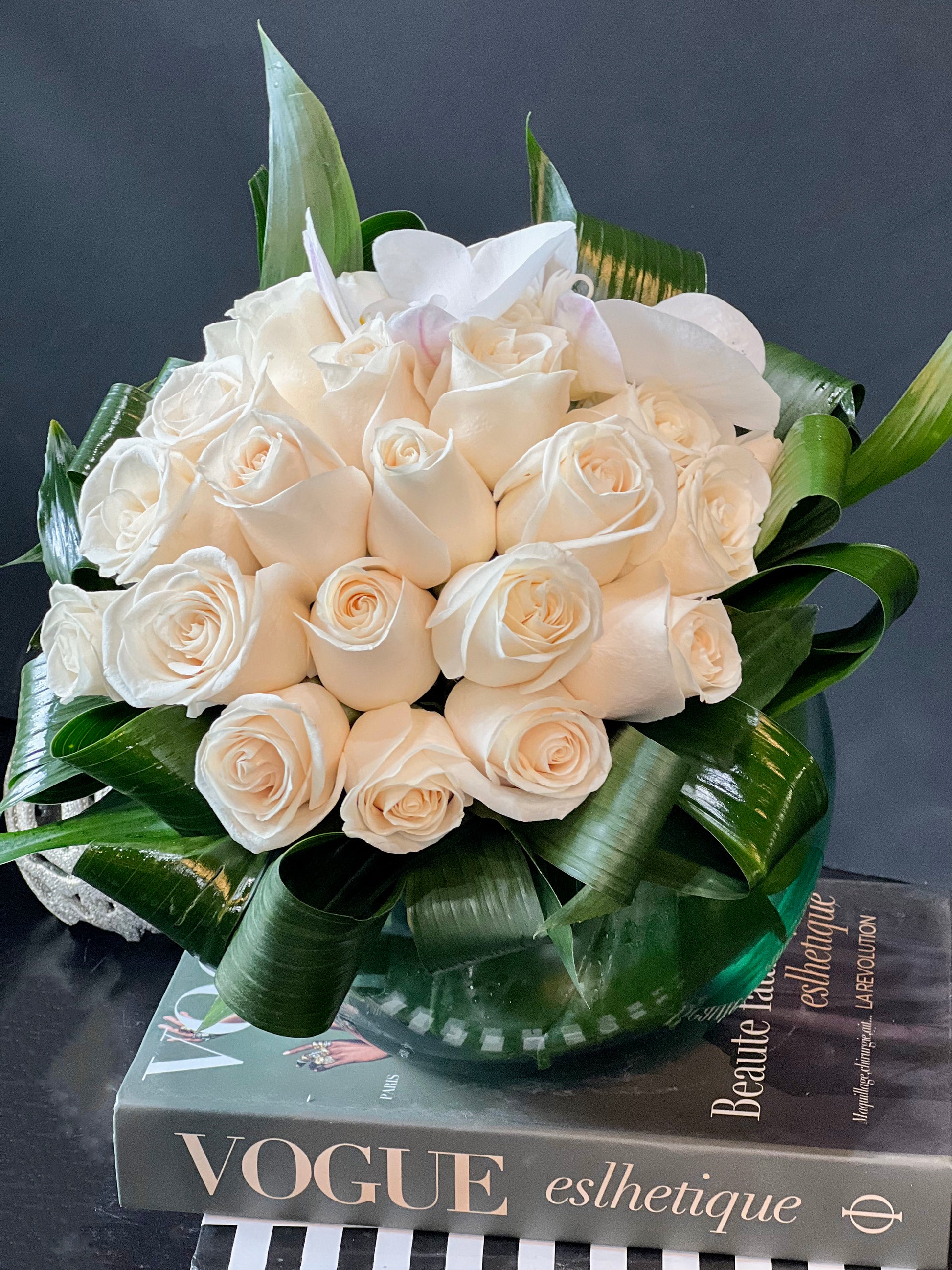 Elegant arrangement of 24 white roses in a glass fishbowl vase by Luxury Flowers Miami