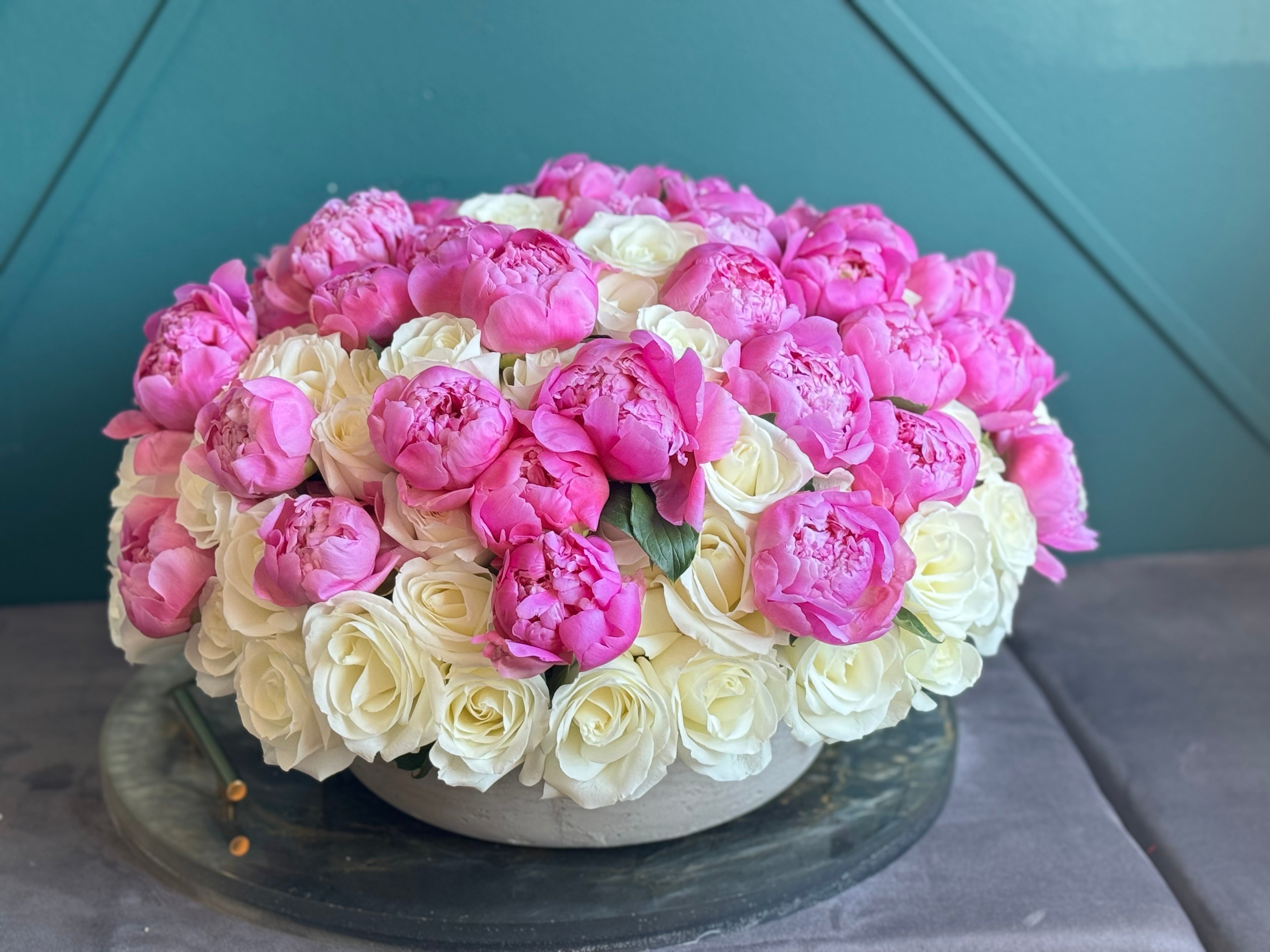 Elegant arrangement of white roses and pink peonies in a modern cement vase