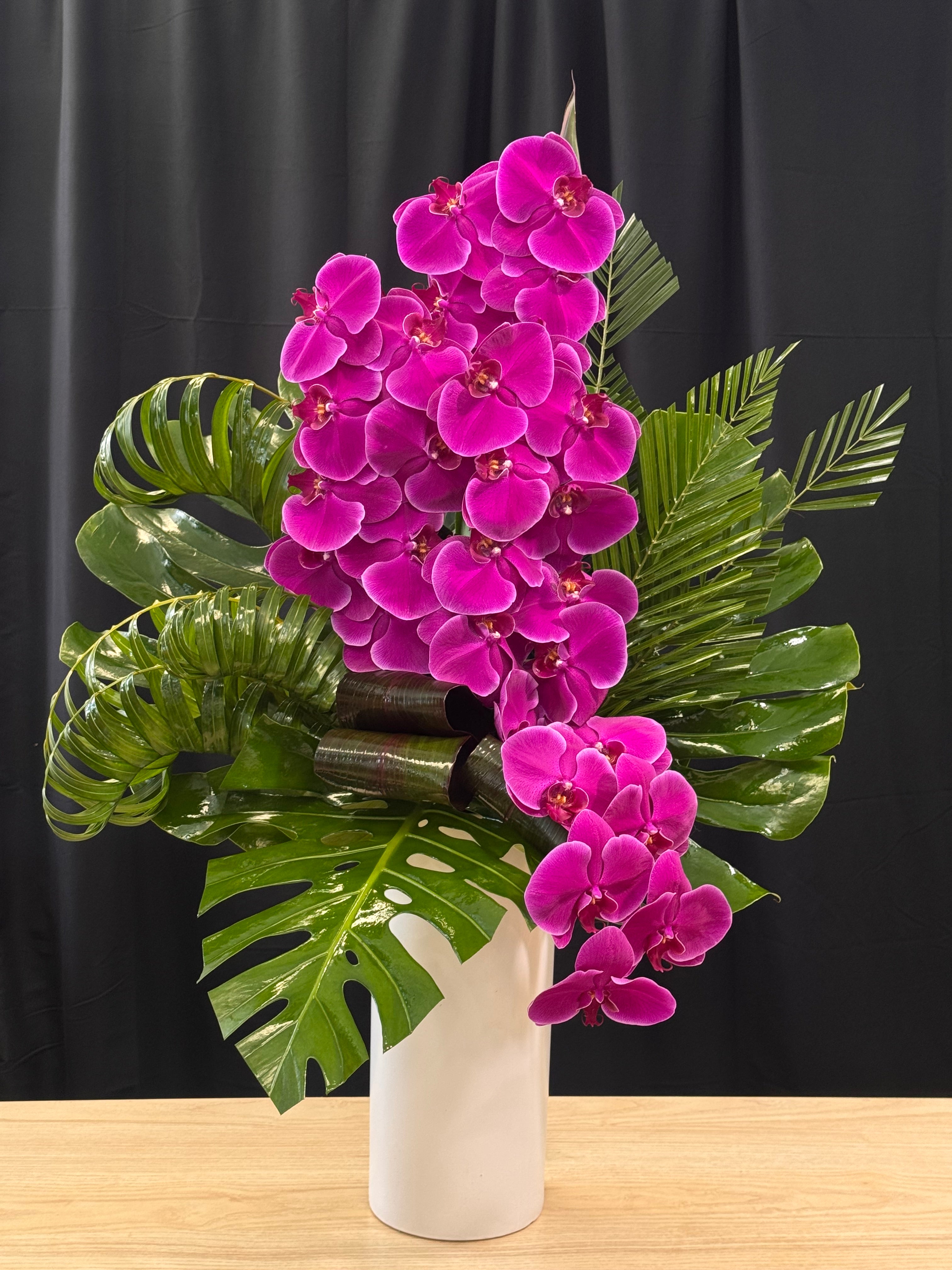 Elegant purple phalaenopsis orchids with tropical greenery in a modern vase