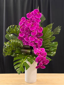 Elegant purple phalaenopsis orchids with tropical greenery in a modern vase