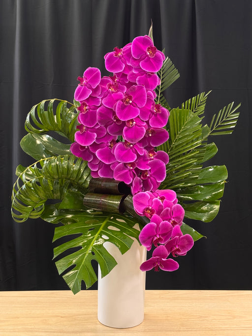 Elegant purple phalaenopsis orchids with tropical greenery in a modern vase