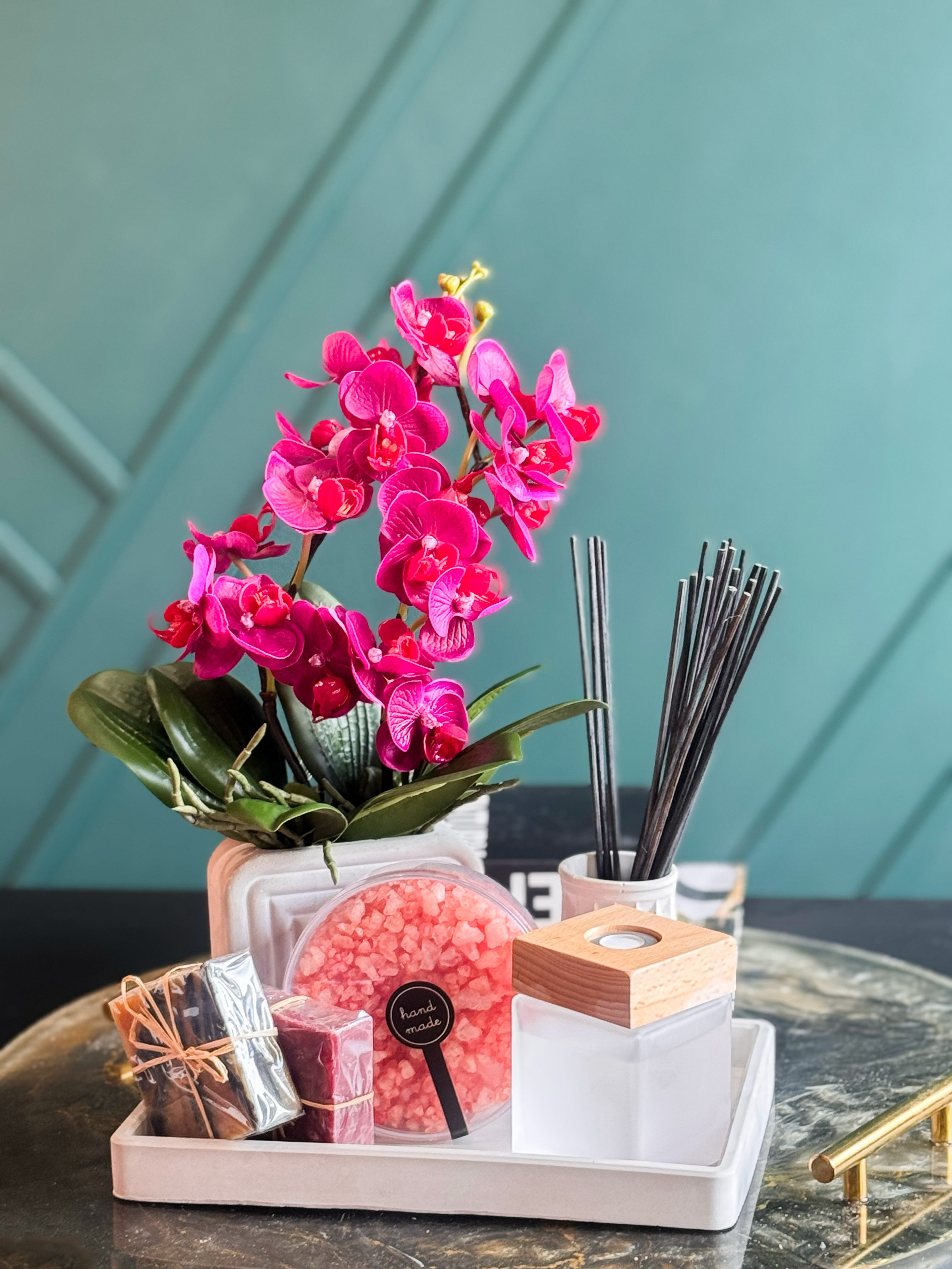 Elegant spa gift basket featuring faux orchid, artisan soap, bath salts and reed diffuser for home relaxation.
