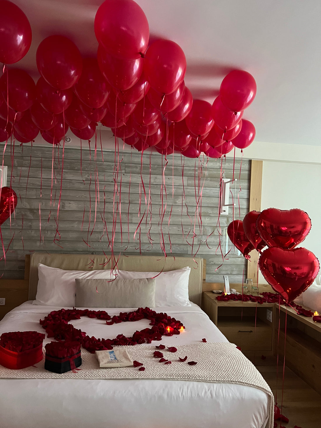 Romantic hotel room decoration Miami with red ceiling balloons and rose petals