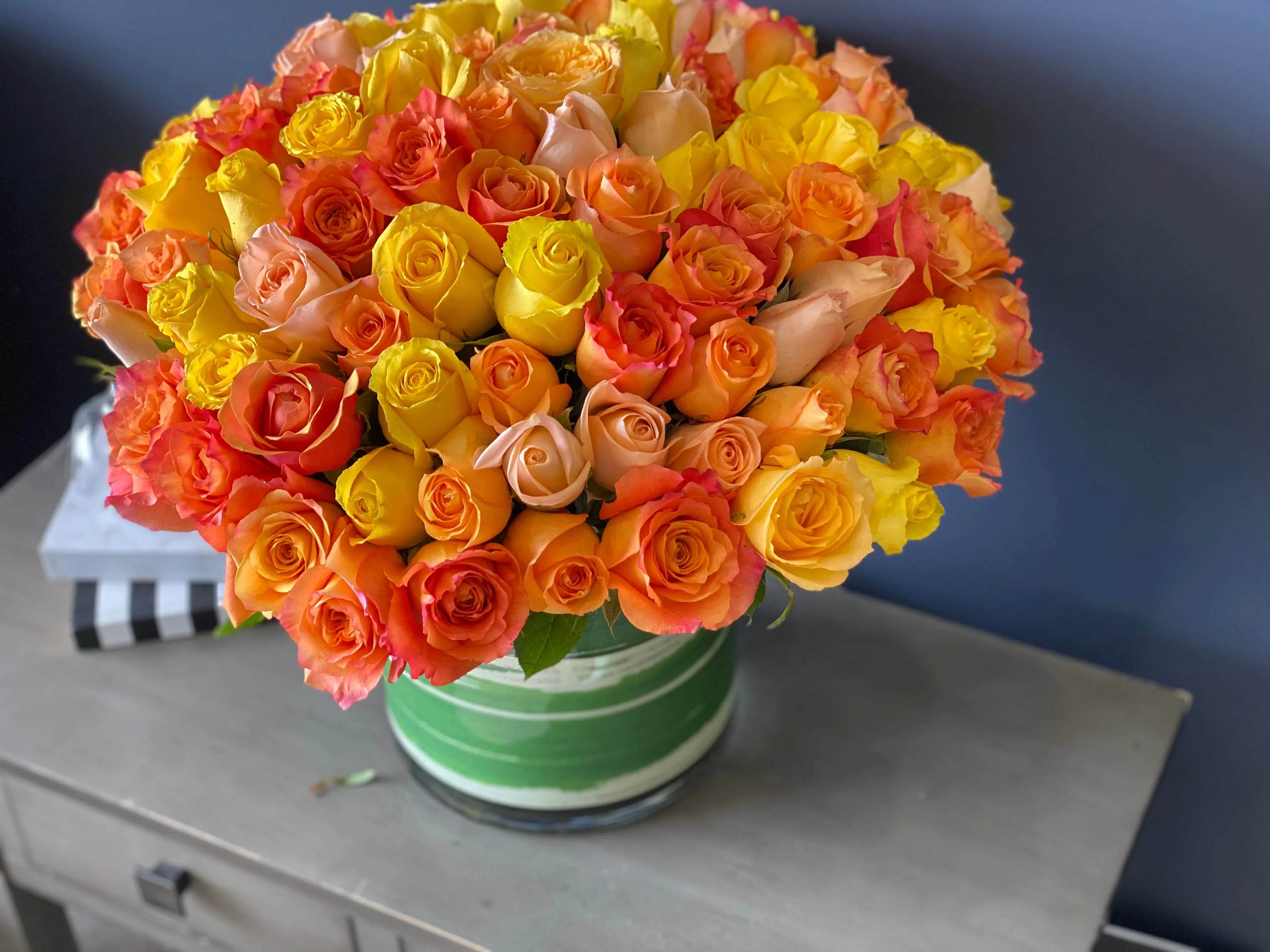 Large 100 rose flower arrangement in warm sunset colors