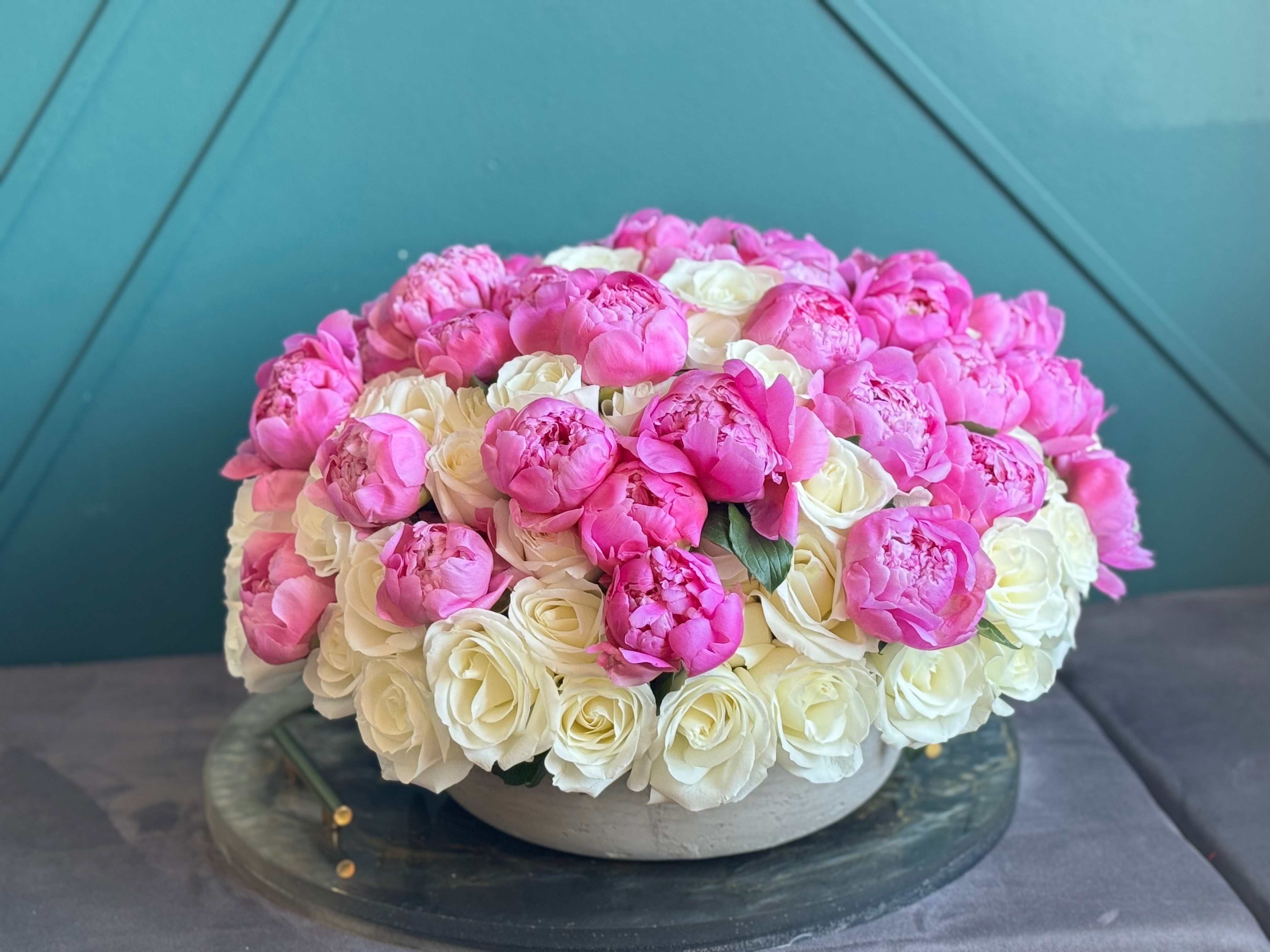 Luxury arrangement of 100 white roses and 50 peonies in a cement vase by Luxury Flowers Miami