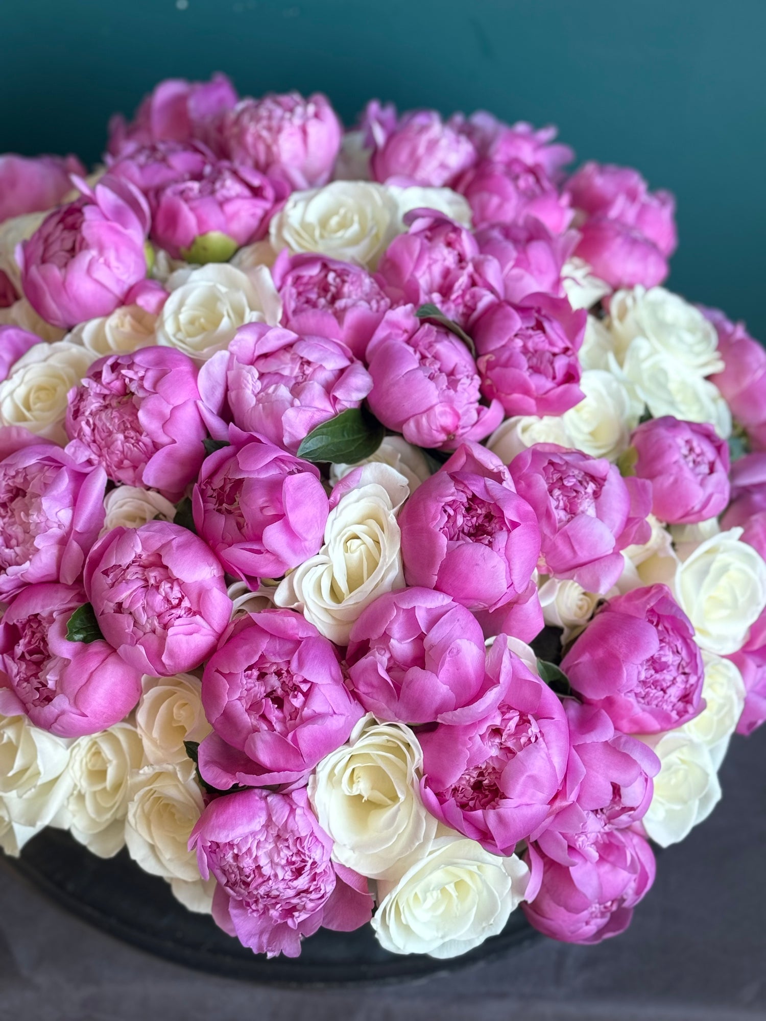 Modern cement vase filled with white roses and pink peonies