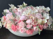 Peonies roses orchids arrangement in a cement bowl