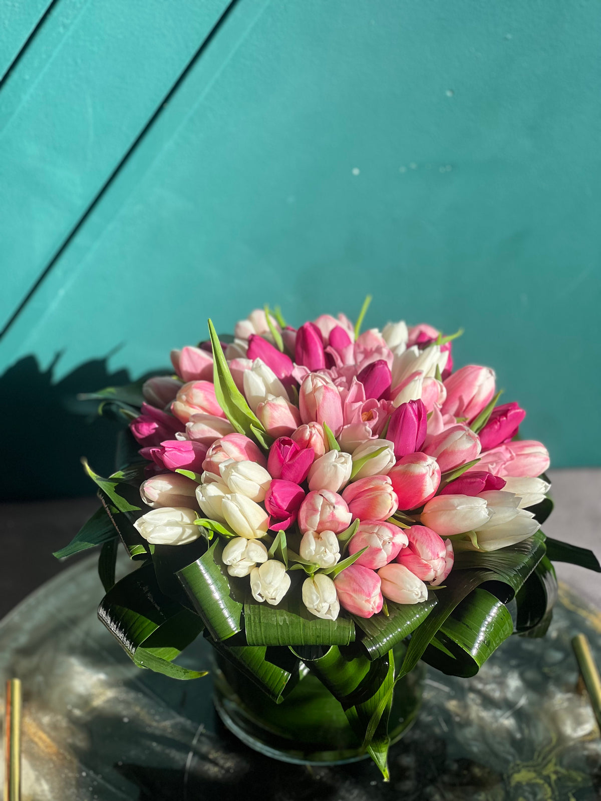 Pink and white tulips with decorative greenery in vase