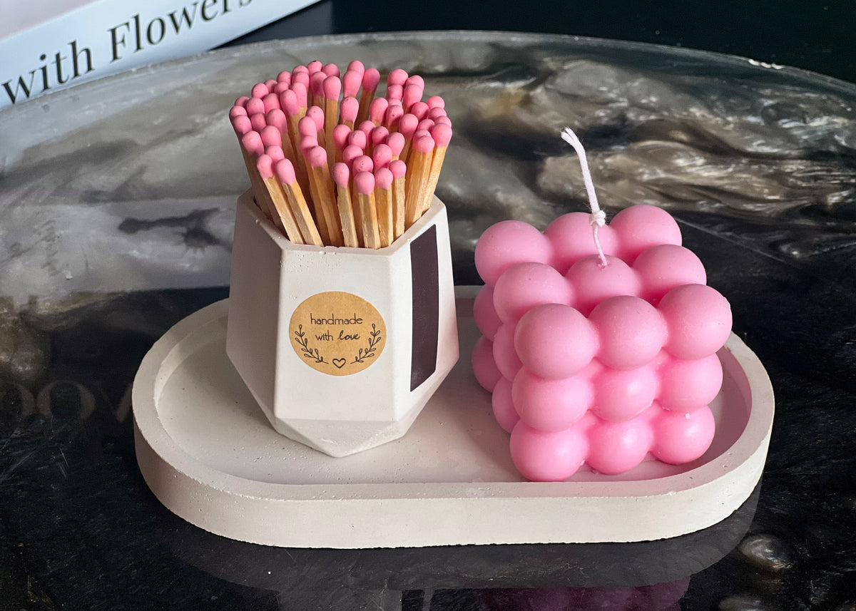 Pink scented candle and matches set on handcrafted cement tray