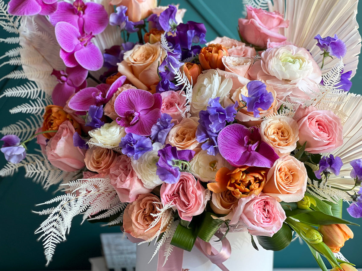 Purple Phalaenopsis orchids with pink and peach roses