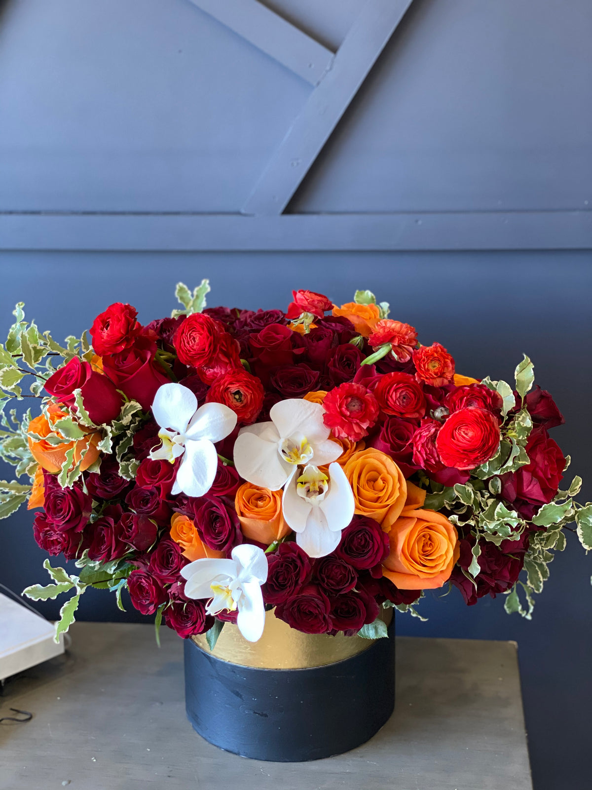 Red and orange rose flower box with white orchids