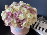 Roses and ranunculus flower arrangement in a round box