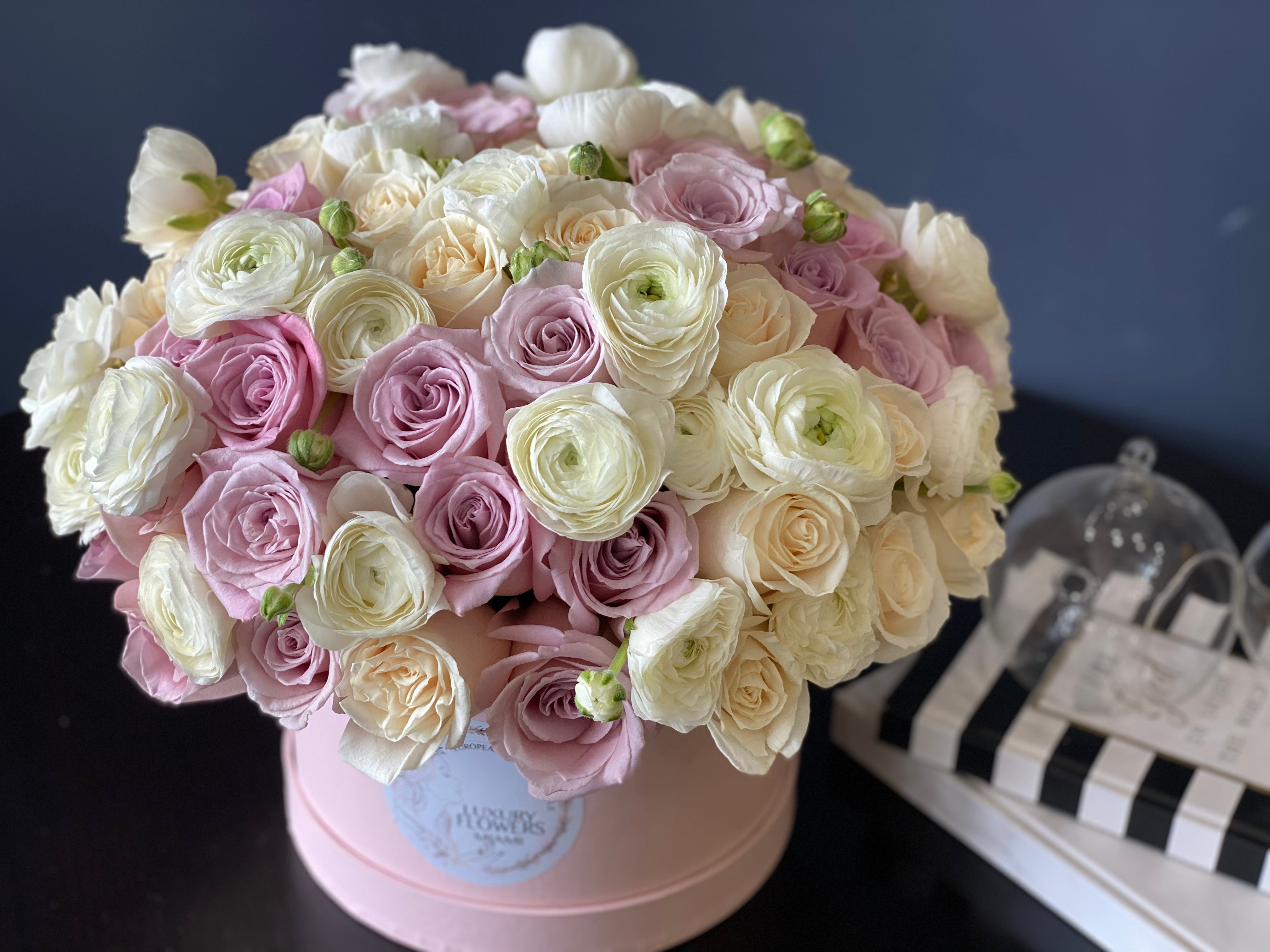Roses and ranunculus flower arrangement in a round box