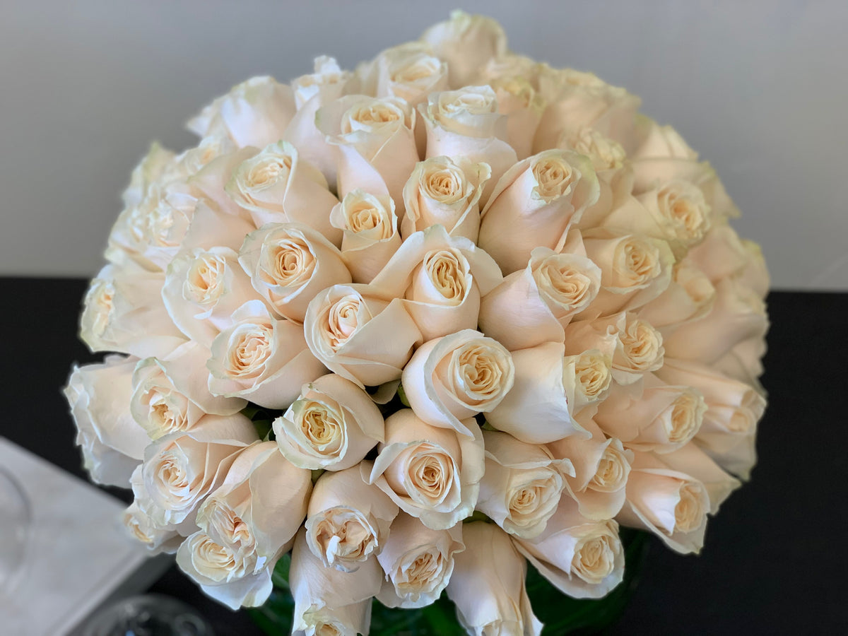 Round white rose arrangement in clear glass vase