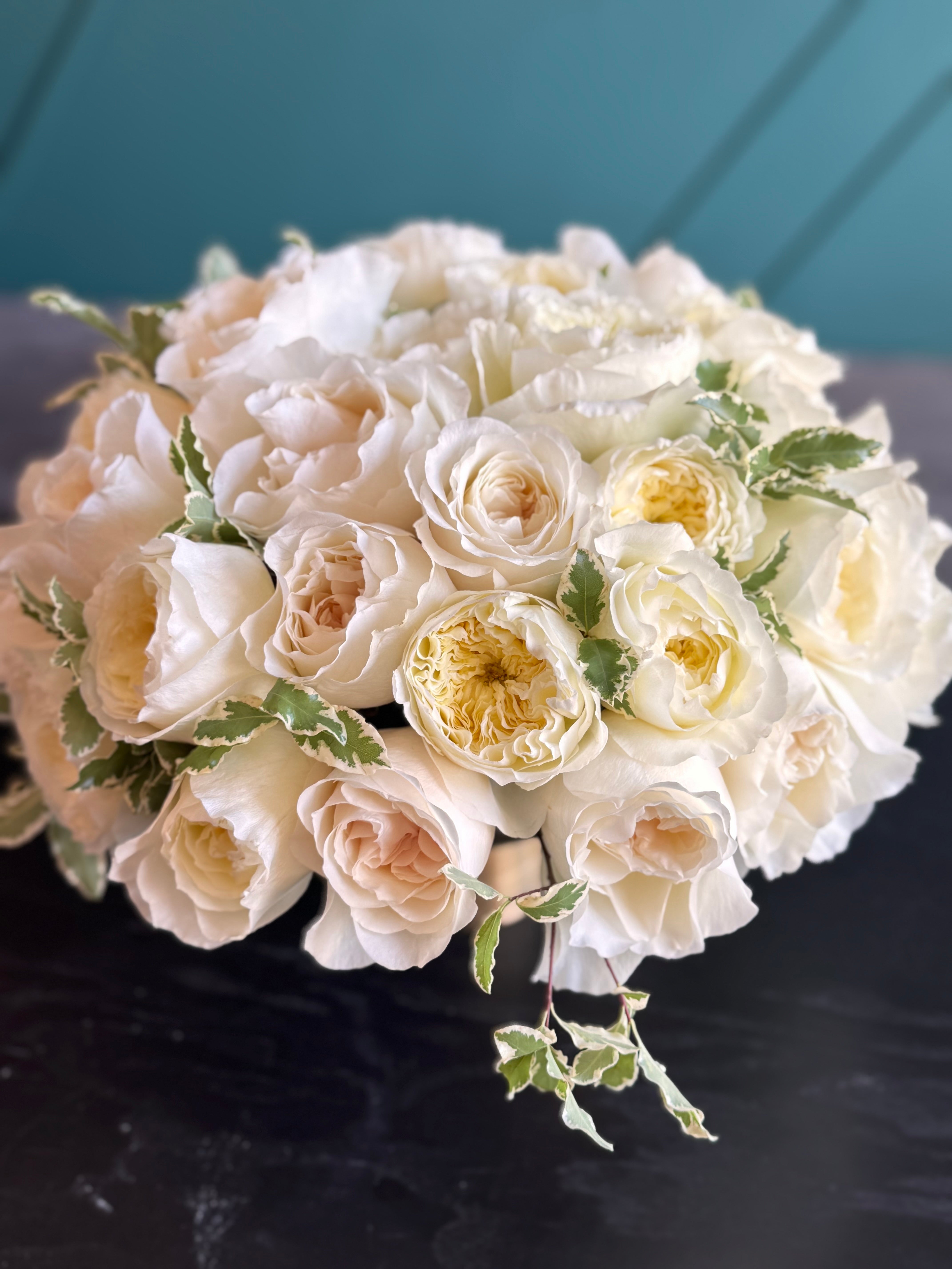 Soft cream garden roses with greenery in an elegant floral arrangement