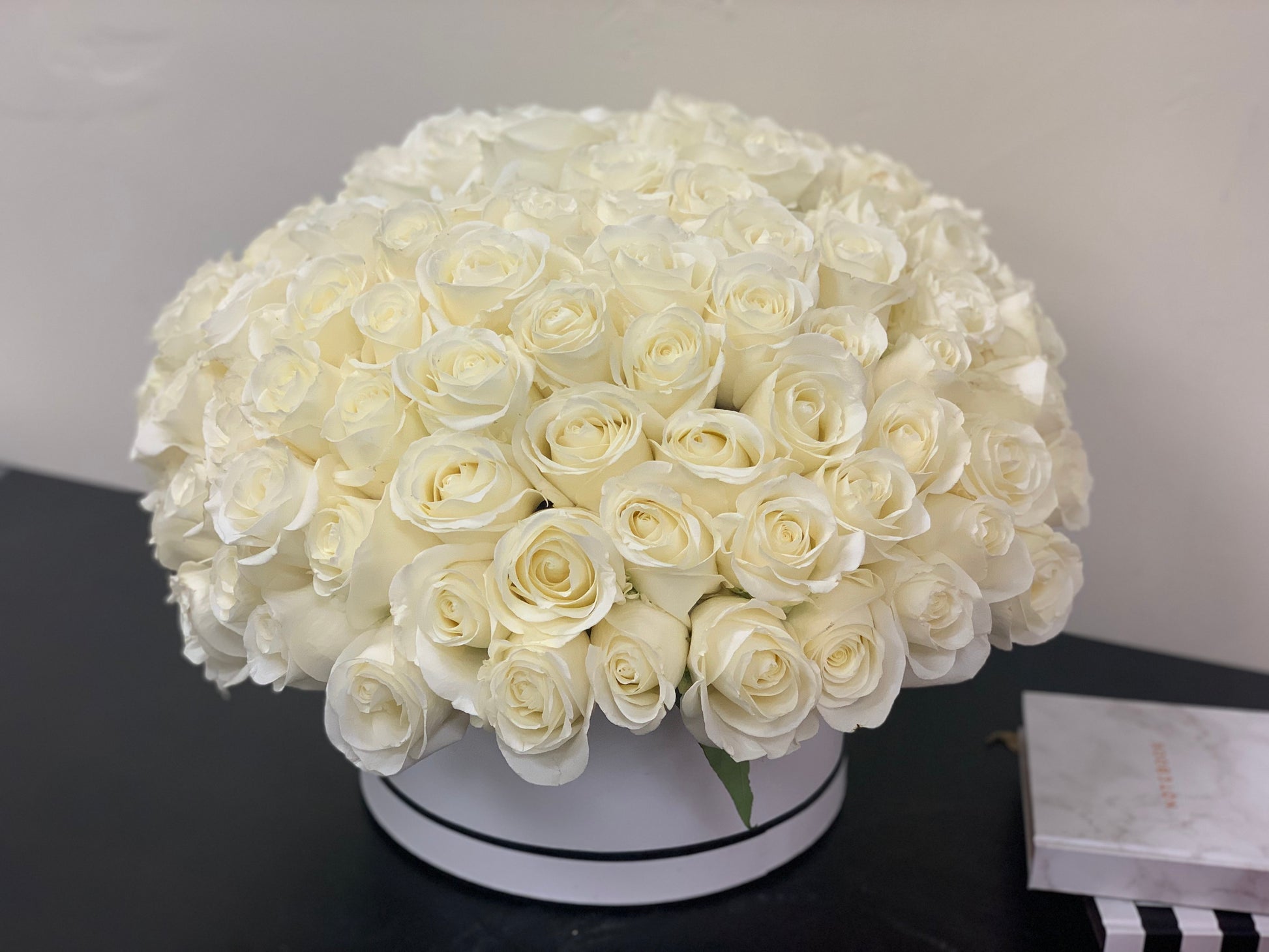 Sophisticated white rose arrangement in a round box with 100 roses