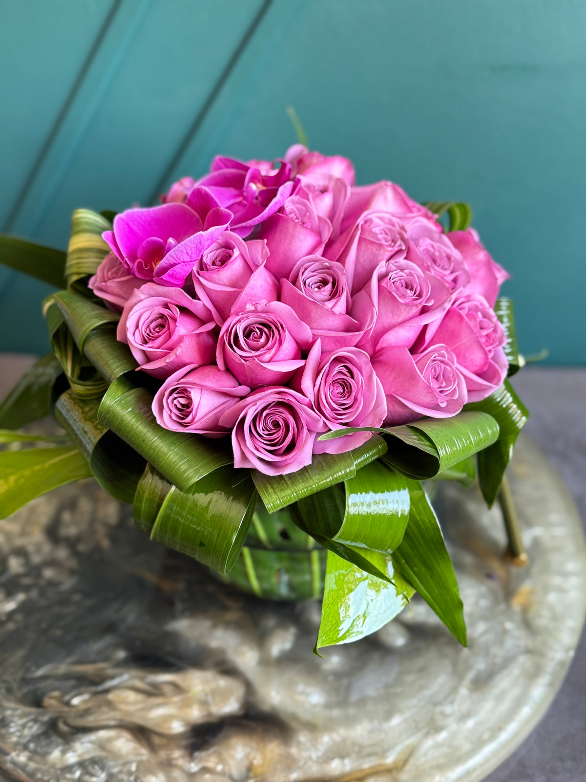 Two dozen purple roses in round glass vase