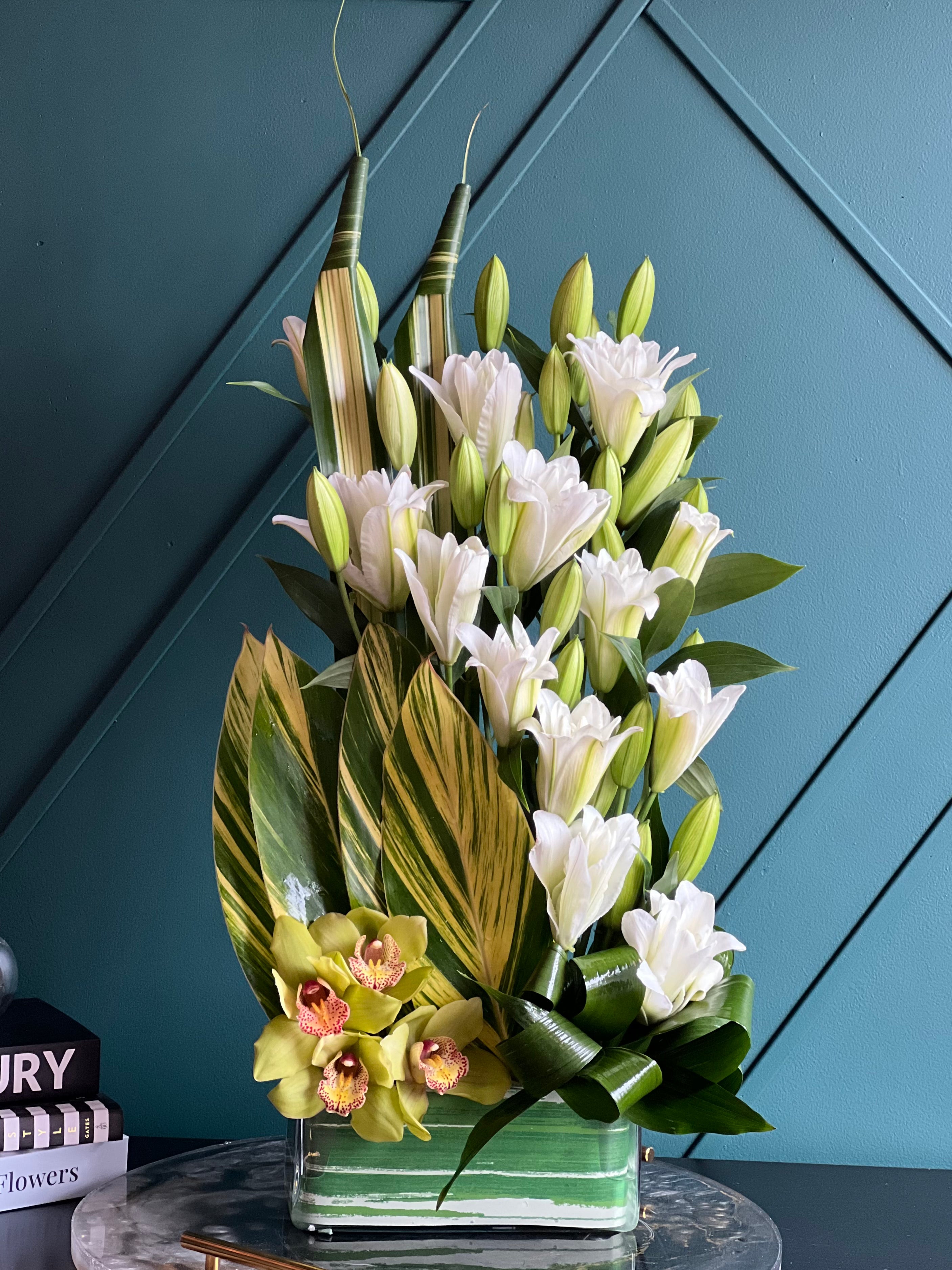 White lilies and green cymbidium orchids with tropical greenery