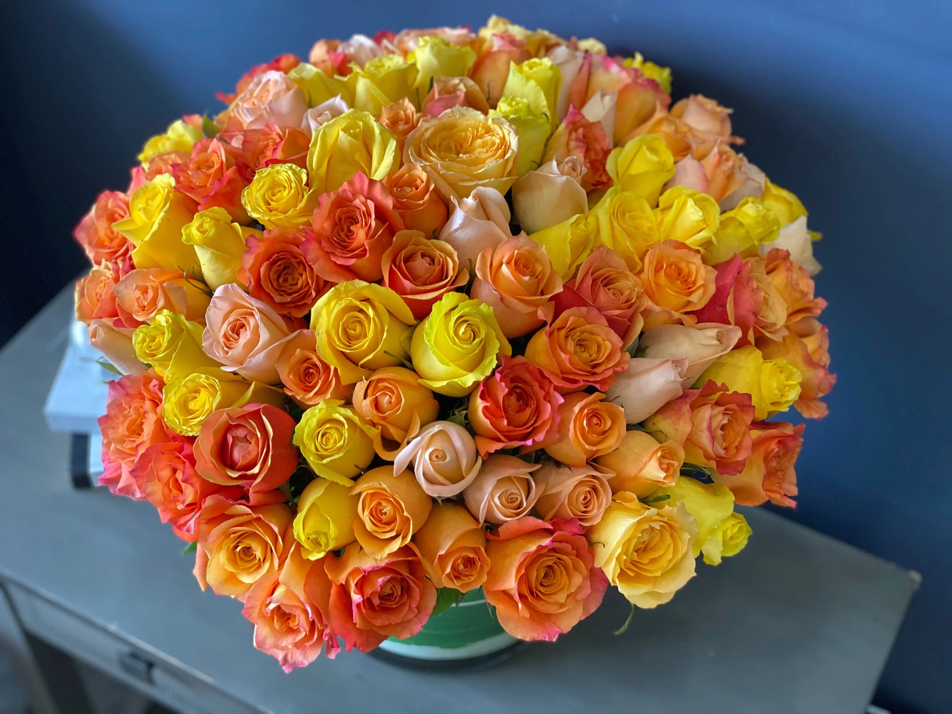 Yellow orange and peach roses arranged in an elegant vase